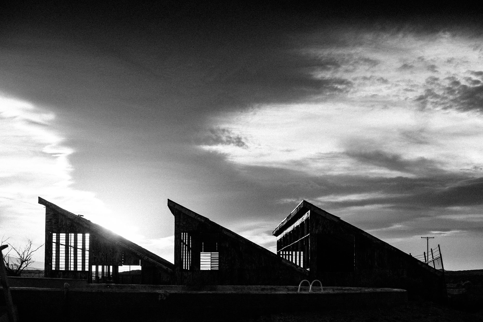 Angular Mojave Ranch buildings beneath a dramatic desert sunset.